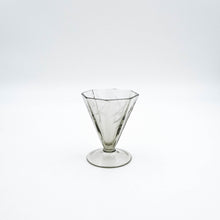 Carica l'immagine nel visualizzatore di Gallery, Servizio di bicchieri anni 30 in vetro fumè di forma ottagonale completo per sei persone, composto da cinque bicchieri per ogni posto tavola e due bottiglie per il vino. Particolare del bicchiere da vino rosso. - Complete set of 1930s octagonal smoked glass glasses for six people, consisting of five glasses for each table setting and two bottles for wine. Detail of the red wine glass.