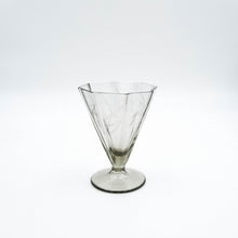 Carica l'immagine nel visualizzatore di Gallery, Servizio di bicchieri anni 30 in vetro fumè di forma ottagonale completo per sei persone, composto da cinque bicchieri per ogni posto tavola e due bottiglie per il vino. Particolare del bicchiere da vino bianco. - Complete set of 1930s octagonal smoked glass glasses for six people, consisting of five glasses for each table setting and two bottles for wine. Detail of the white wine glass.